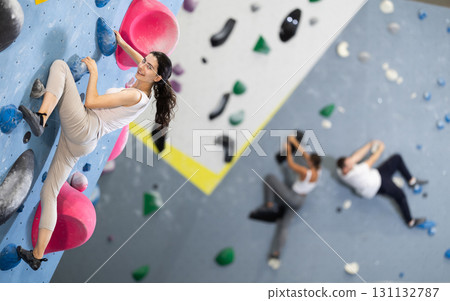 Young woman doing rock climbing on climbing wall 131132787