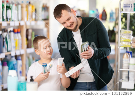 Man and boy choosing toothbrush in store Man and boy choosing toothbrush in store 131132899