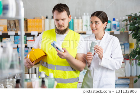 male builder chooses an ointment in a pharmacy 131132906