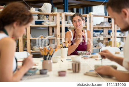 Three craftsperson are busy painting clay products 131133000