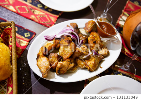 Appetizing pork shish kebab of Georgian cuisine with adzhika and onion 131133049