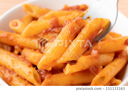 Close-up of penne pasta with meat sauce on a fork 131133163