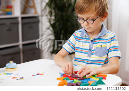 Child Engaged in Creative Play with Colorful Geometric Shapes Child Engaged in Creative Play with Colorful Geometric Shapes 131133302