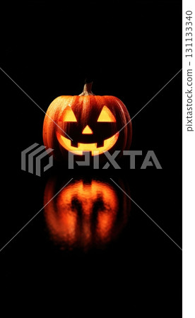 Glowing Jack-o-Lantern on Black Background with Spotlight Effect 131133340