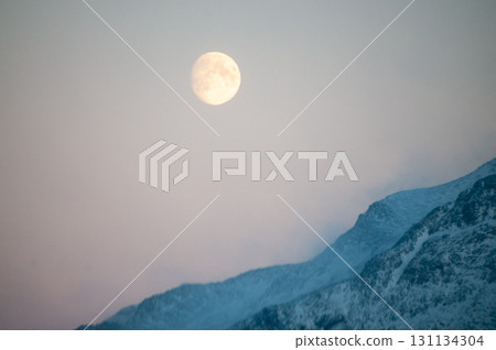 Near full moon slipping behind a mountain 131134304