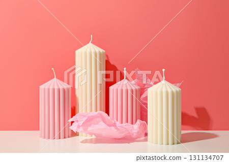 Four decorative candles in pink and white sit on a table 131134707