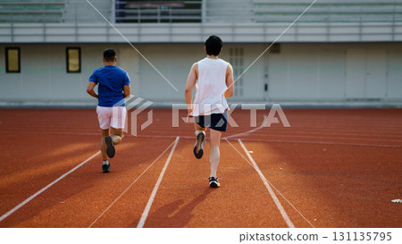 Two asian athlete men or male friends are running together on the racetrack in sports stadium. 131135795