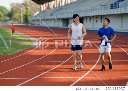 Two asian athlete men or male friends are running together on racetrack in the sports stadium. 131135937