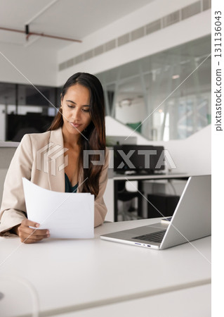 Focused professional expert woman reading legal financial document at workplace 131136043