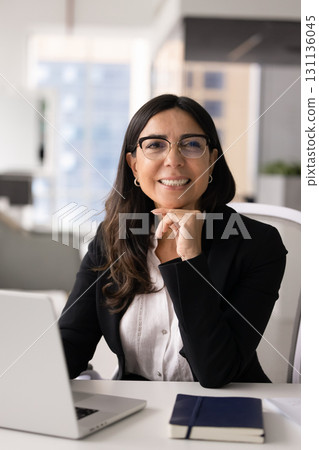 Positive mature business woman wearing elegant eyeglasses, posing at workplace 131136045