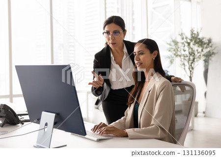 Two diverse business colleagues meeting at computer monitor Two diverse business colleagues meeting at computer monitor 131136095
