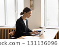 Calm busy young woman type on notebook at office desk 131136096