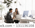 Two young multiethnic coworkers meeting at laptop 131136108