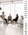 Different aged team of colleagues talking in office workspace 131136111