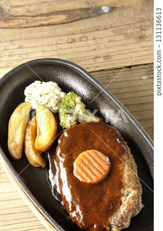 Hamburger steak plate with side dishes of fries, potato salad, and broccoli 131136613