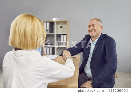Appreciative mature male client shaking hand of trusted female manager Appreciative mature male client shaking hand of trusted female manager 131136664