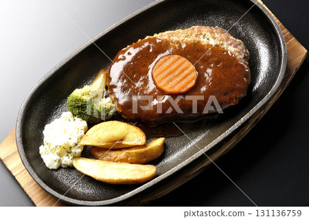 Hamburger steak plate with side dishes of fries, potato salad, and broccoli photographed against a black background Hamburger steak plate with side dishes of fries, potato salad, and broccoli photographed against a black background 131136759