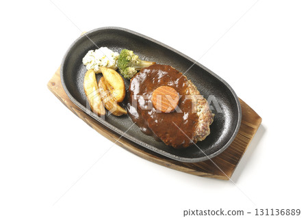 Hamburger steak plate with side dishes of fries, potato salad, and broccoli photographed against a white background 131136889