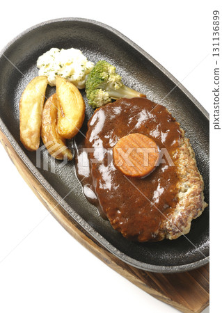 Hamburger steak plate with side dishes of fries, potato salad, and broccoli photographed against a white background 131136899