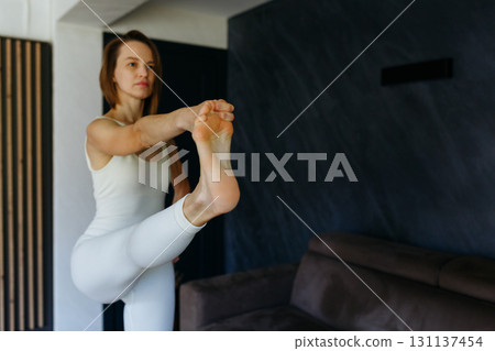 one woman standing Hand to Big Toe yoga pose at home 131137454