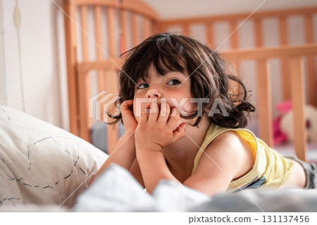 portrait of a small child lying on the bed at home looking aside 131137456