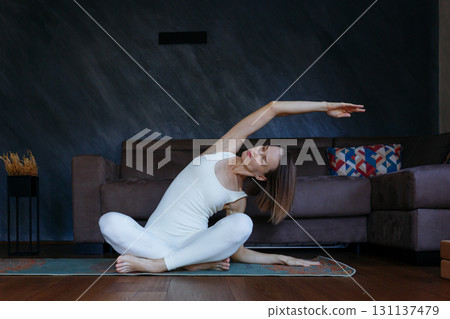 woman doing yoga at home stretching an arm woman doing yoga at home stretching an arm 131137479