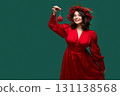 Happy woman in red dress holding Christmas ornament 131138568