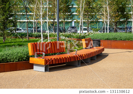Contemporary wooden bench in landscaped park area with green grass and seasonal flowers. comfortable urban environment. improvement, beautification, renovation of urban environment 131138612