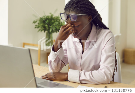 Tired, stressed African American business woman suffering from headache and eye strain 131138776
