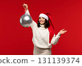Smiling woman in Santa hat holding large silver ornament. 131139374