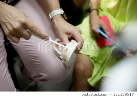 Engaging children in a dental hygiene activity, an instructor illustrates effective teeth brushing techniques using a model and toothbrush. 131139517