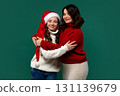 Mum and teenage daughter hug in festive sweaters, smiling warmly 131139679
