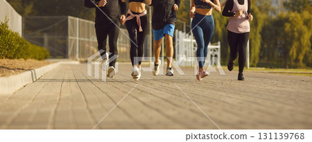 Team of people men and women running together in city park having sport workout outdoors. 131139768
