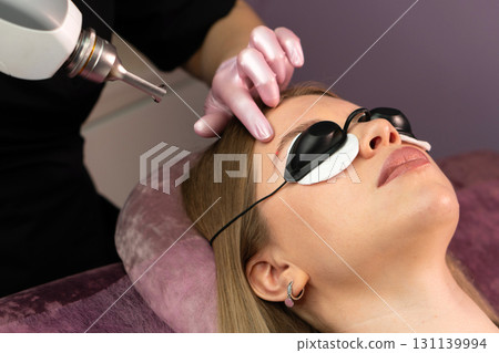 Esthetician examines eyebrow alignment before laser tattoo removal procedure 131139994