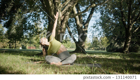 young beautiful white girl doing yoga in park among trees in clearing on summer day young beautiful white girl doing yoga in park among trees in clearing on summer day 131140071