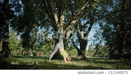 young beautiful white girl doing yoga in park among trees in clearing on summer day young beautiful white girl doing yoga in park among trees in clearing on summer day 131140073