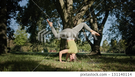 young beautiful white girl doing yoga in park among trees in clearing on summer day 131140114