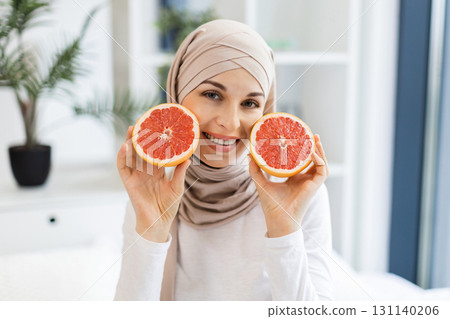 Beautiful young Muslim woman enjoying healthy lifestyle holding fresh grapefruits in bright space. Promotes well-being, skincare, fresh produce. Ideal for wellness, health, fruit Beautiful young Muslim woman enjoying healthy lifestyle holding fresh grapefruits in bright space. Promotes well-being, skincare, fresh produce. Ideal for wellness, health, fruit 131140206