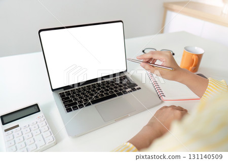 Work from Home. Professional woman using laptop for remote work with notebook and calculator. 131140509