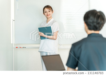 Female staff including nurses, pharmacists, and registered dietitians explaining in front of a whiteboard at a medical conference 131140783