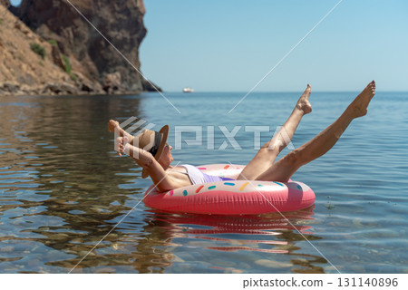 Woman relaxing water. Young woman floating on inflatable donut ring in clear blue sea for summer vacation happiness. 131140896