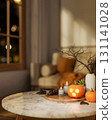 Glowing craves jack-o-lantern halloween pumpkin and candles on wooden tray over table in living room 131141028