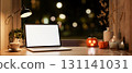 Blank screen laptop with coffee and halloween pumpkin with candle on wood table near window at night 131141031