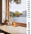 Flowering branch in vase and halloween pumpkin with candles on wooden table aside window in sunlight 131141033