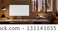 White screen computer on table with halloween pumpkin lanterns and candles on window in dim lit room 131141035