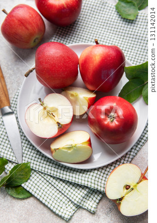 Fresh red apples whole and sliced on white plate with green leaves 131142014