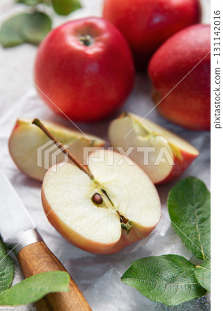 Freshly cut red apples on baking paper with knife and leaves Freshly cut red apples on baking paper with knife and leaves 131142016