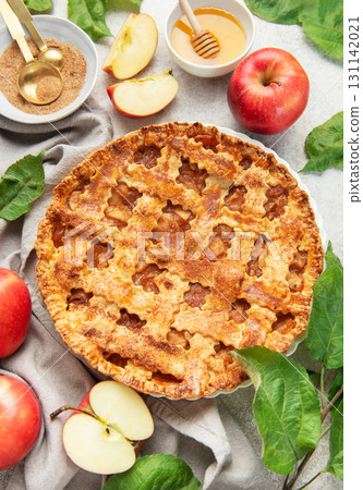Freshly baked apple pie decorated with apple slices and leaves on marble background 131142021