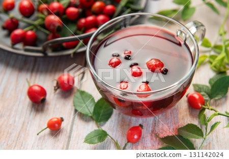 Steaming rosehip tea with fresh rose hips on rustic wooden table Steaming rosehip tea with fresh rose hips on rustic wooden table 131142024