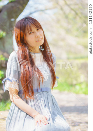 A middle-aged Japanese woman surrounded by cherry blossoms in full bloom 131142130